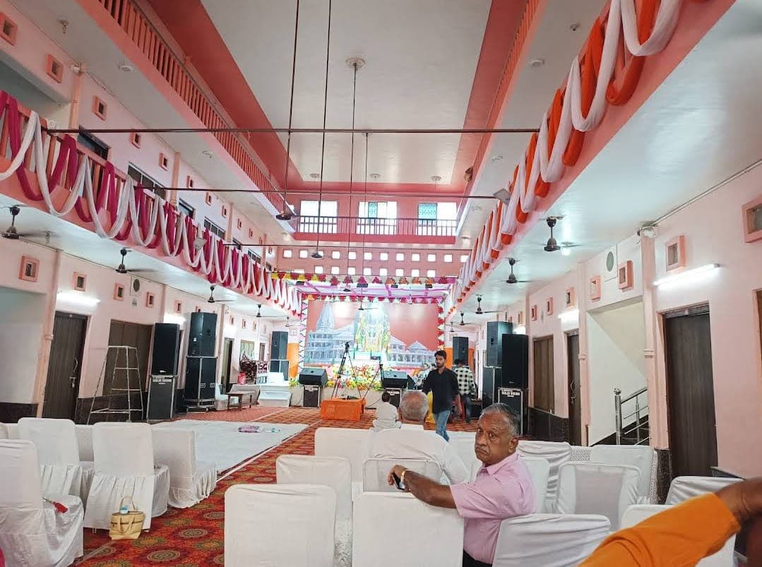 Decorated satsang hall with saffron and white drapes and rows of chairs